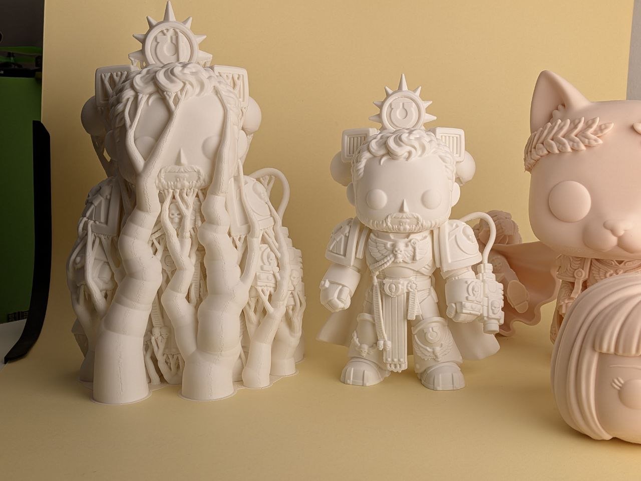 Dettaglio delle figure chiare stampate in 3D, con un guerriero ancora nei supporti ad albero e uno senza supporti