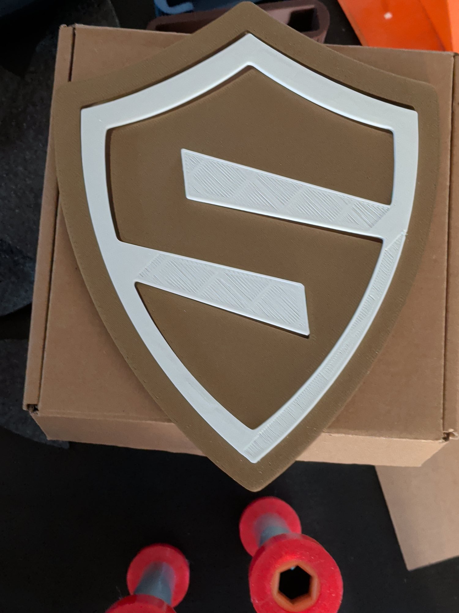 Scudo del logo stampato in 3D con la maschera di centraggio bianca inserita, prova di montaggio