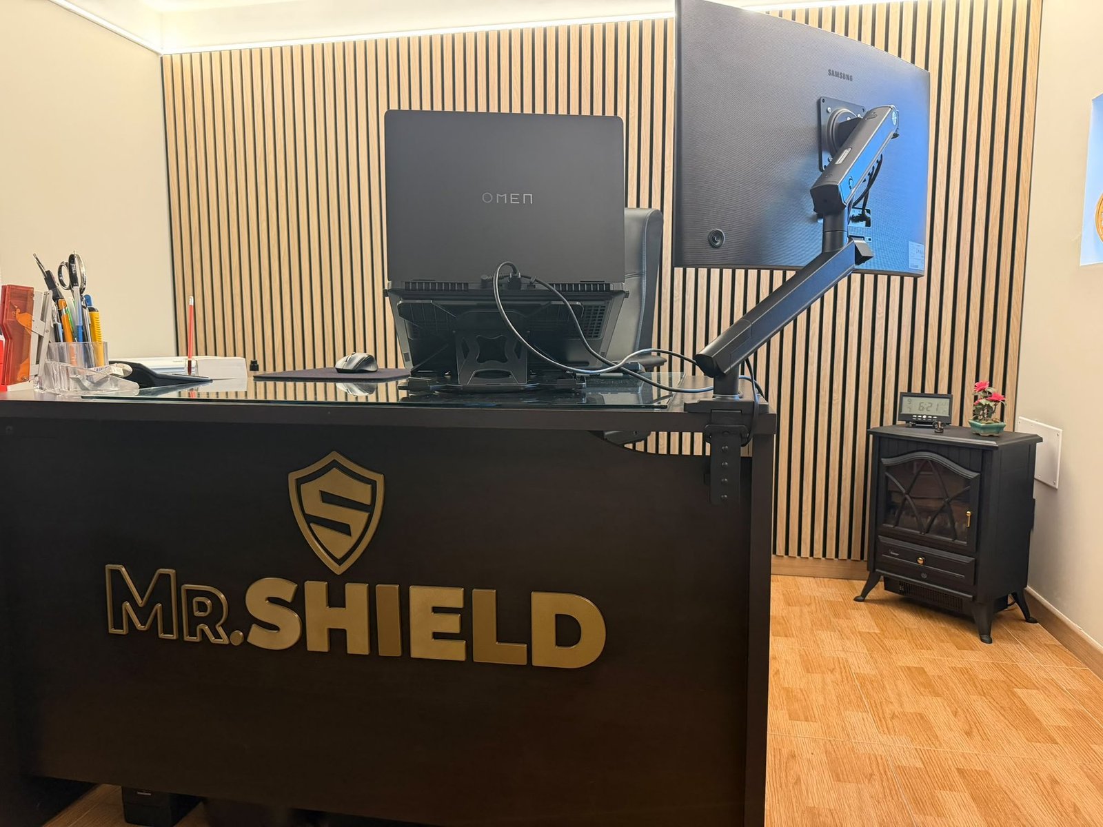 Insegna in rilievo color oro con scudo e scritta Mr Shield montata sul fronte di un bancone nero in ufficio, stampa 3D Torino